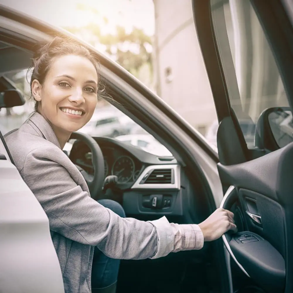 Femme assise dans une voiture et souriant à la camera